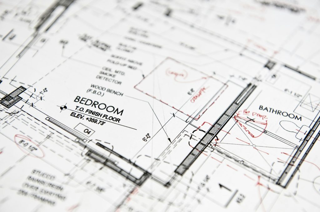 Closeup of a blue print, architects drawing with red pen alterations,